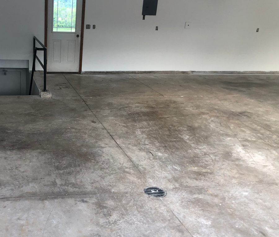 A garage before installation, with stained and worn bare concrete.
