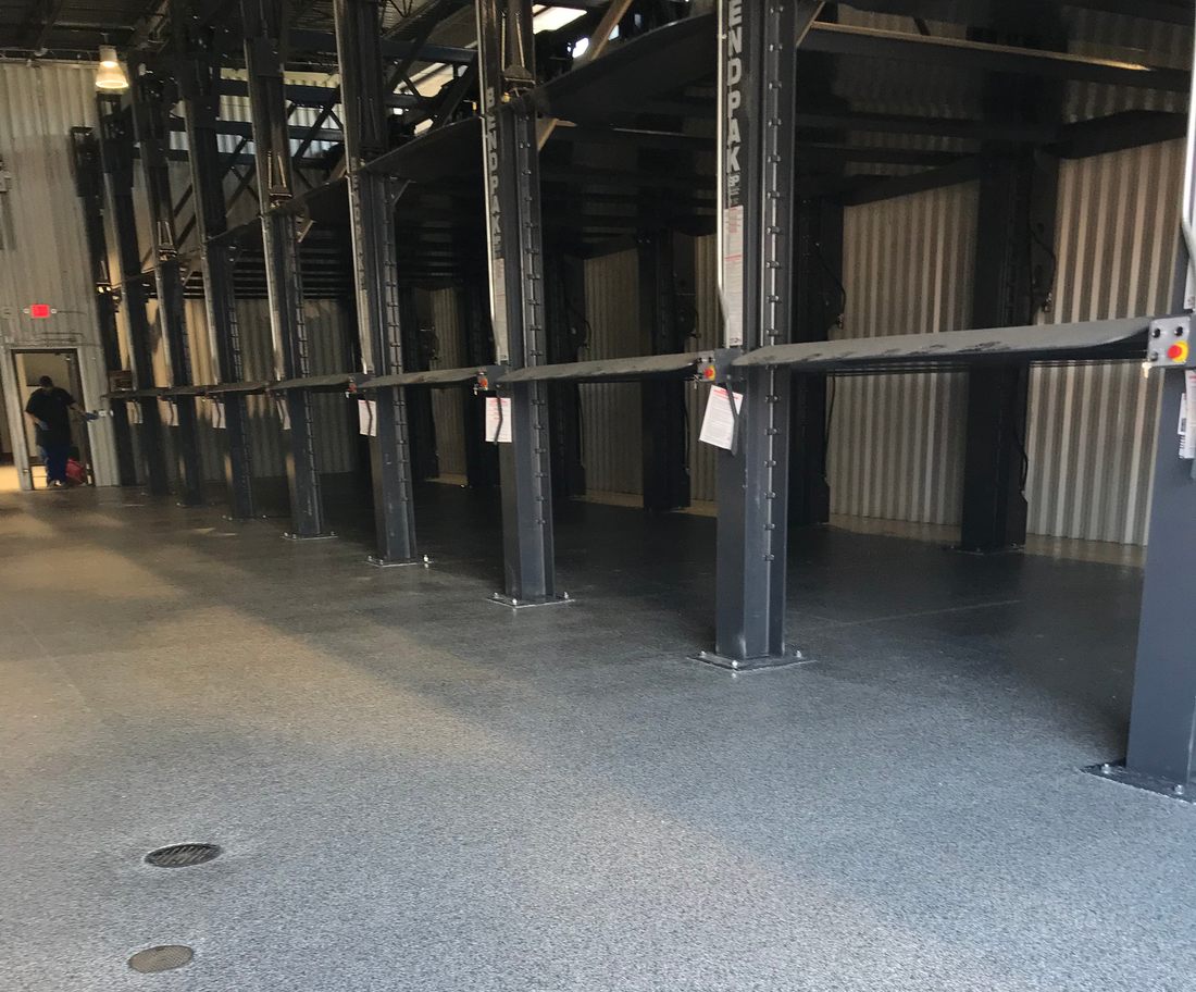 Industrial bay with steel columns and lifts standing on a coated floor.