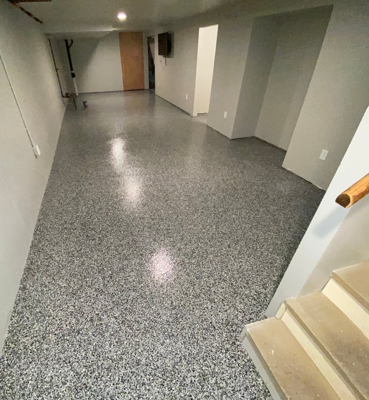 Finished basement floor in a dark flake blend, running past the stair landing.